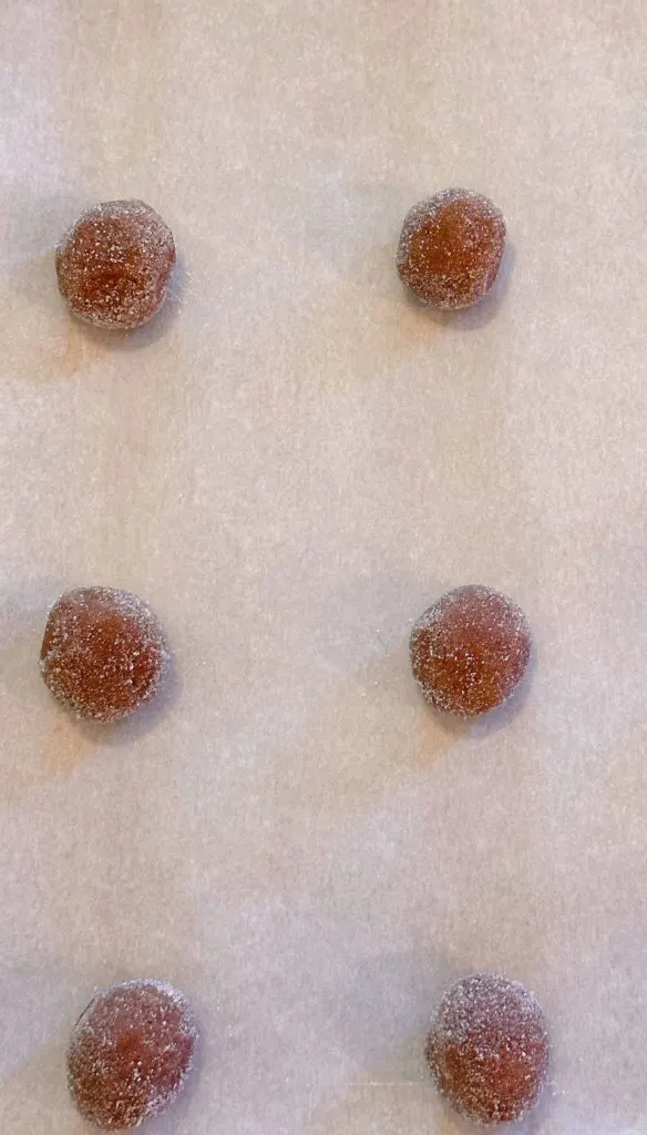 Cookie dough balls on a parchment lined baking sheet.