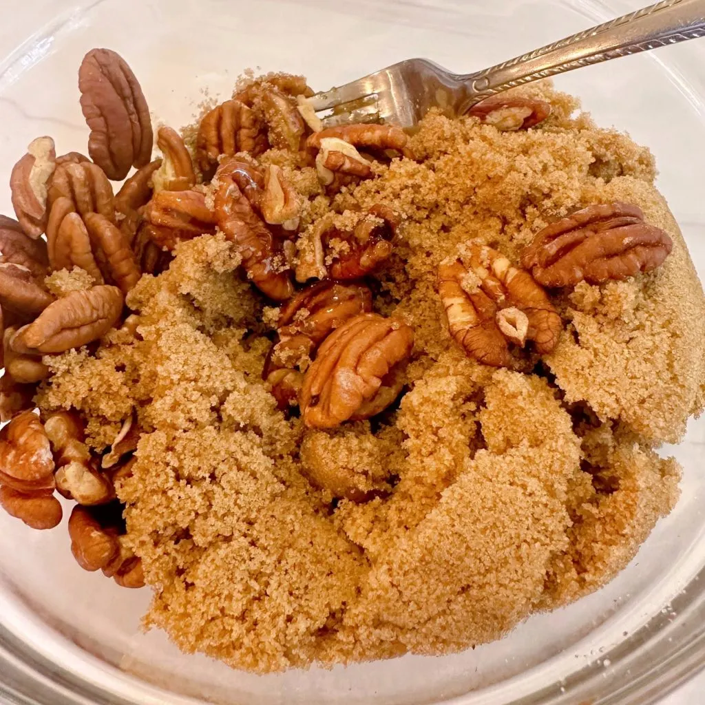 Pecans and brown sugar mixture in a bowl for crispy pecan topping.