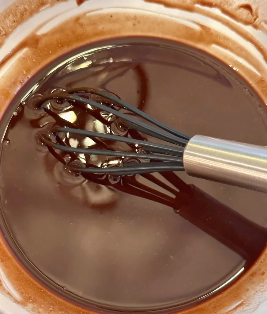 Stirring melted chocolate and butter until smooth.