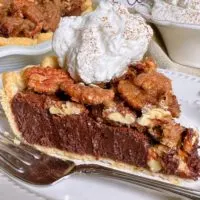 Close-up photo of Chocolate Pecan Chess Pie slice with whipped cream.