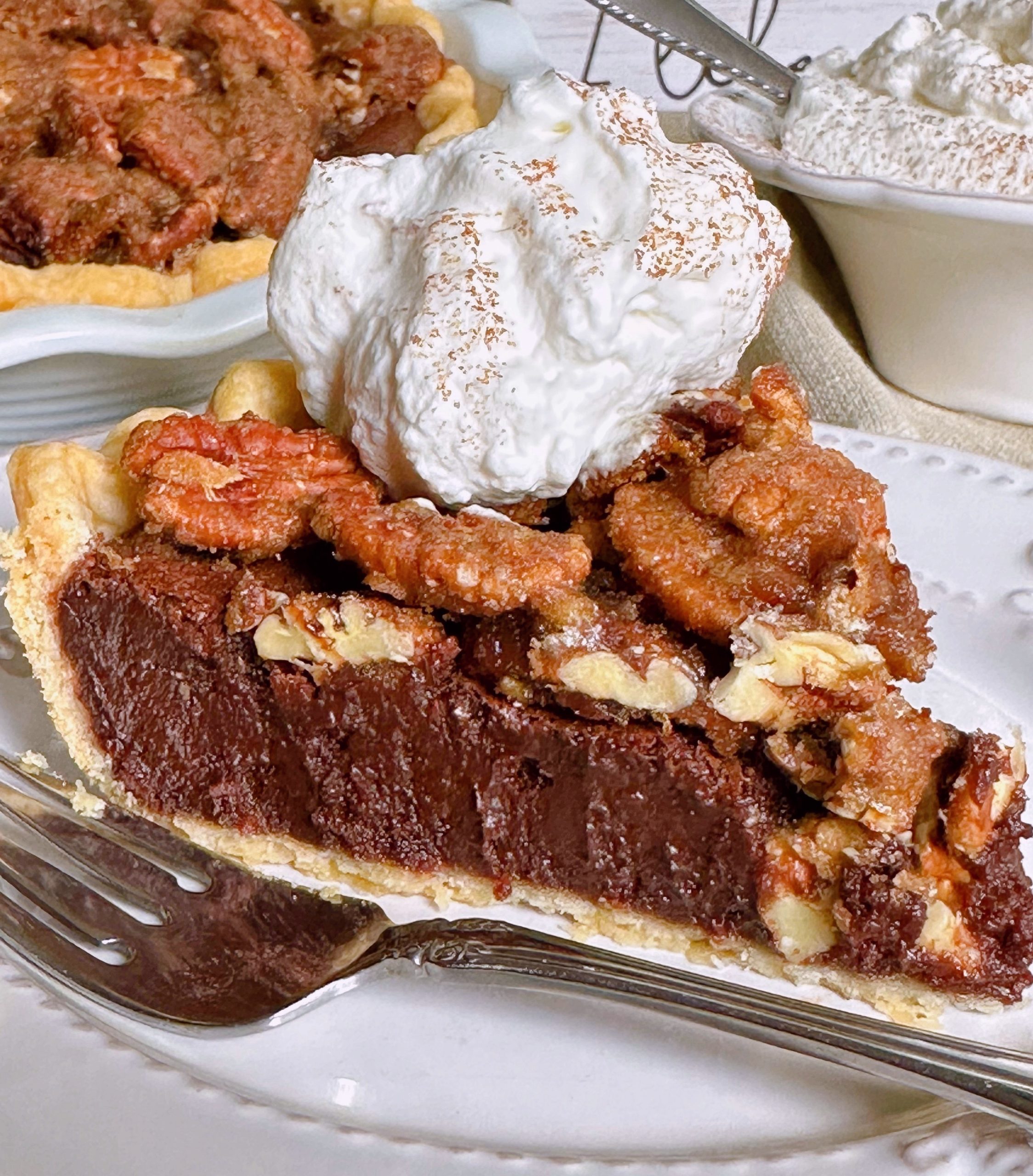 Close-up photo of Chocolate Pecan Chess Pie slice with whipped cream.