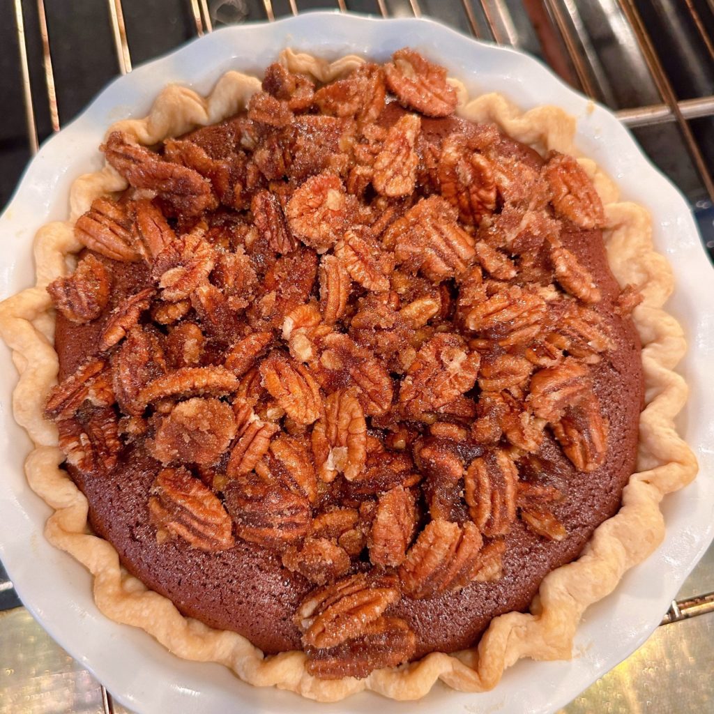 Placing sugar pecans on the top of the chocolate pie filling and baking in the oven.