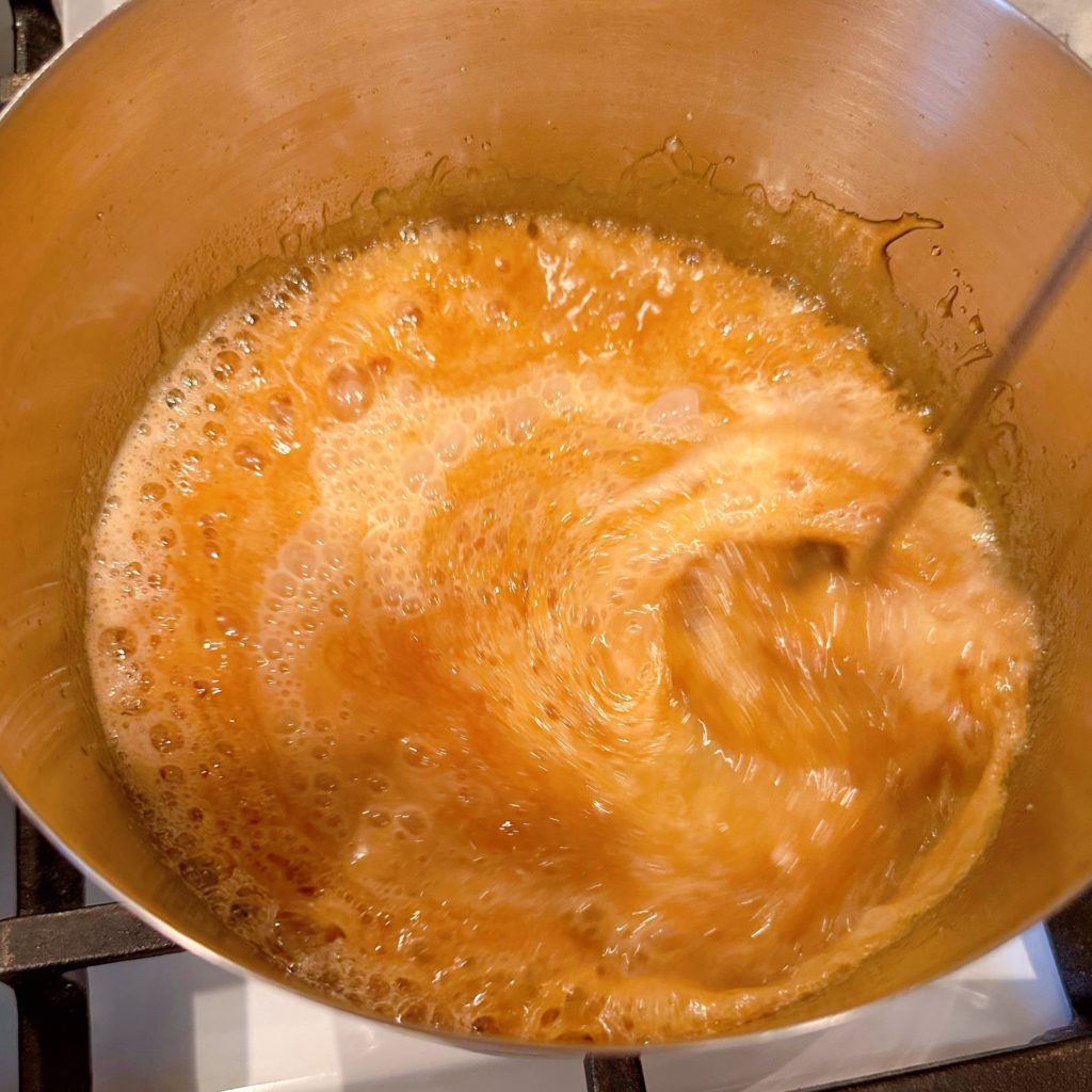 Whisking cream into caramel sauce.