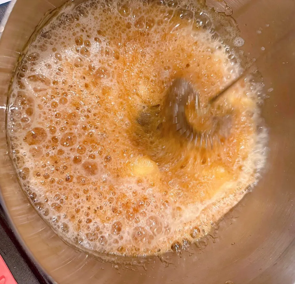 Adding butter to boiled sugar water mixture.