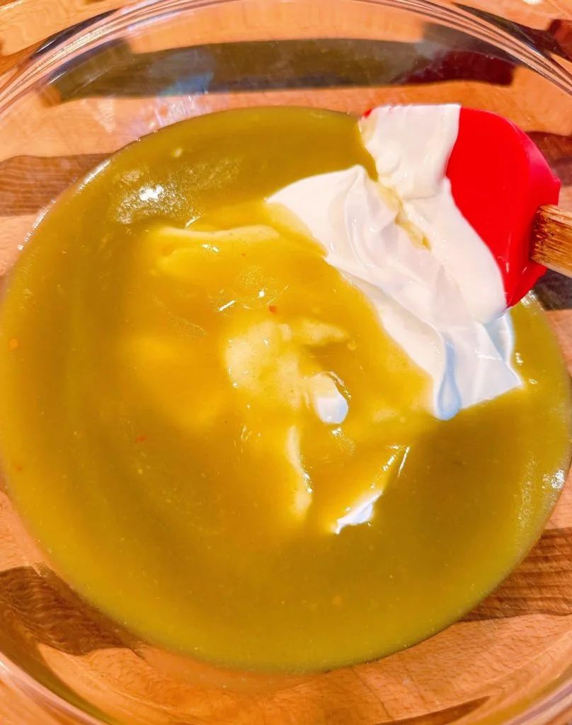 Green enchilada sauce and sour cream in a medium bowl.