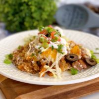 Serving of Walking taco casserole on a white plate with taco toppings.