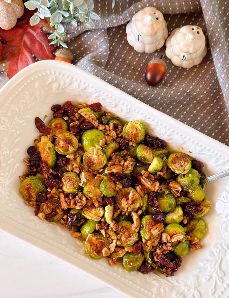 Overhead shot of Roasted Brussels Sprouts with pecans and cranberries in a white serving bowl.