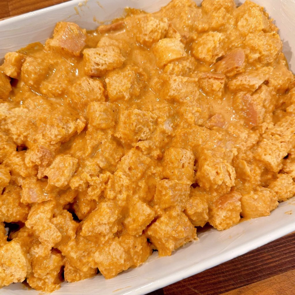 Pumpkin bread pudding pressed down in baking dish ready for the oven.