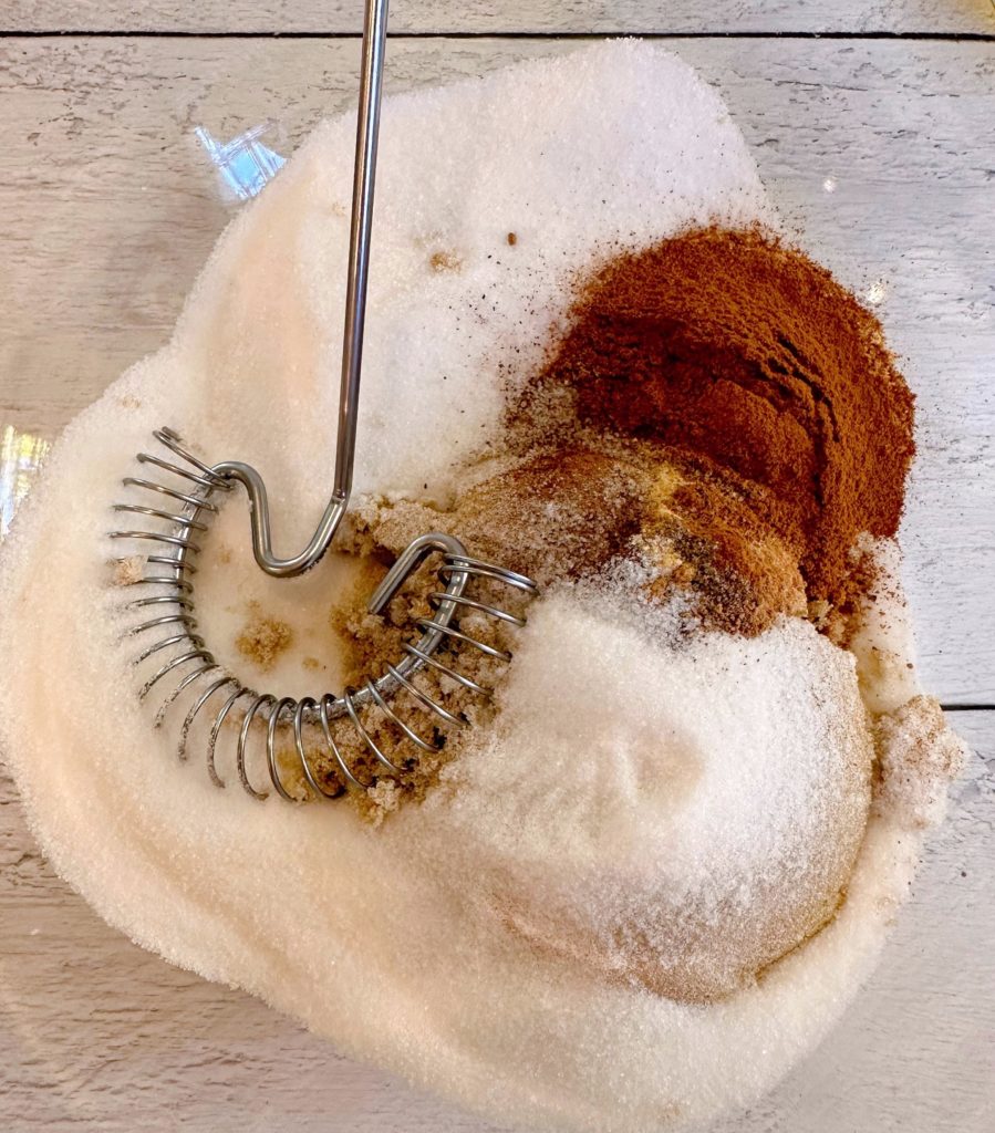 Mixing sugars and spices in a large bowl for pumpkin bread pudding.