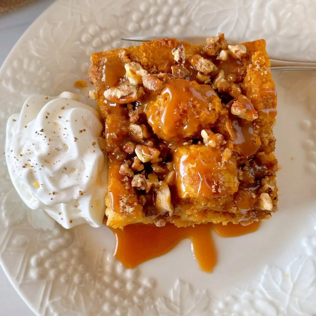Pumpkin Pecan Bread Pudding with caramel sauce and a side of whipped cream.