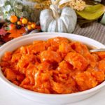 Candied Yams in a white serving dish with a serving spoon.