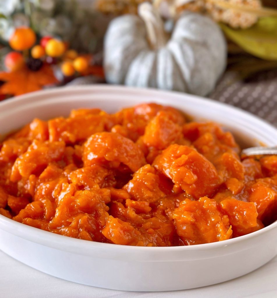 Dish full of Candied Yams with Fall table decor in the background.