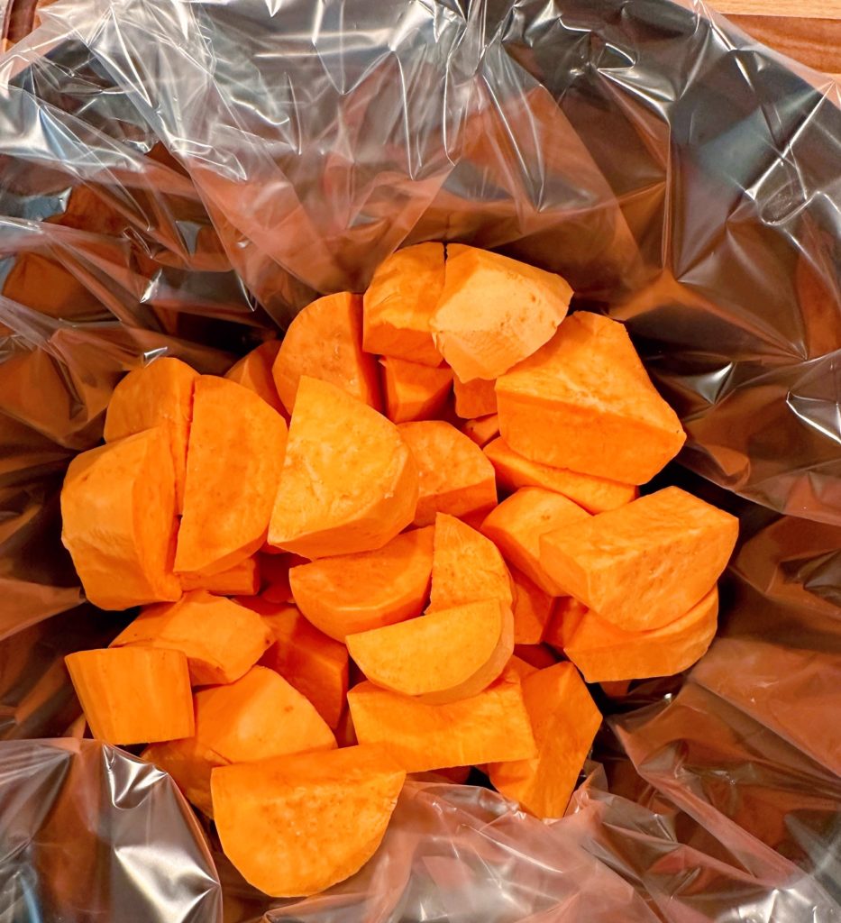 Sweet potatoes in the bottom of a lined slow cooker.