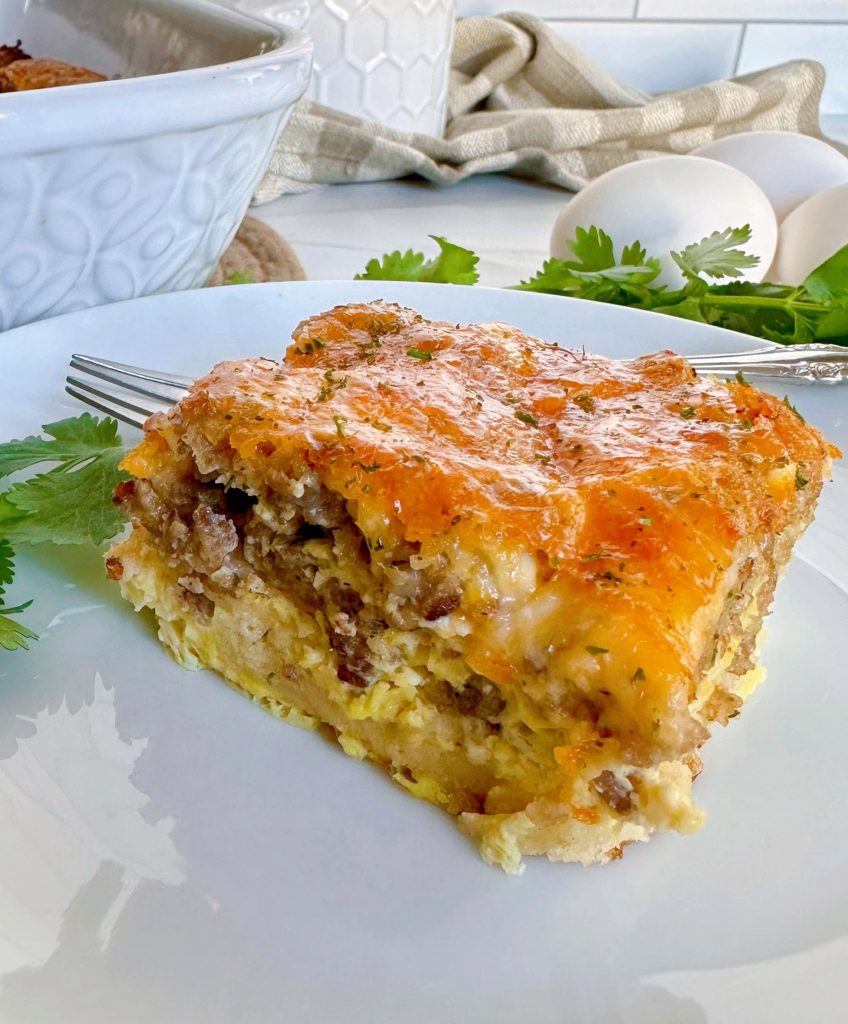 Christmas Crescent Roll Breakfast Casserole piece on a white plate with a fork.