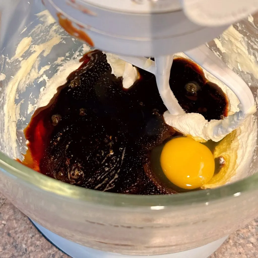 Adding molasses and egg to creamed butter mixture.