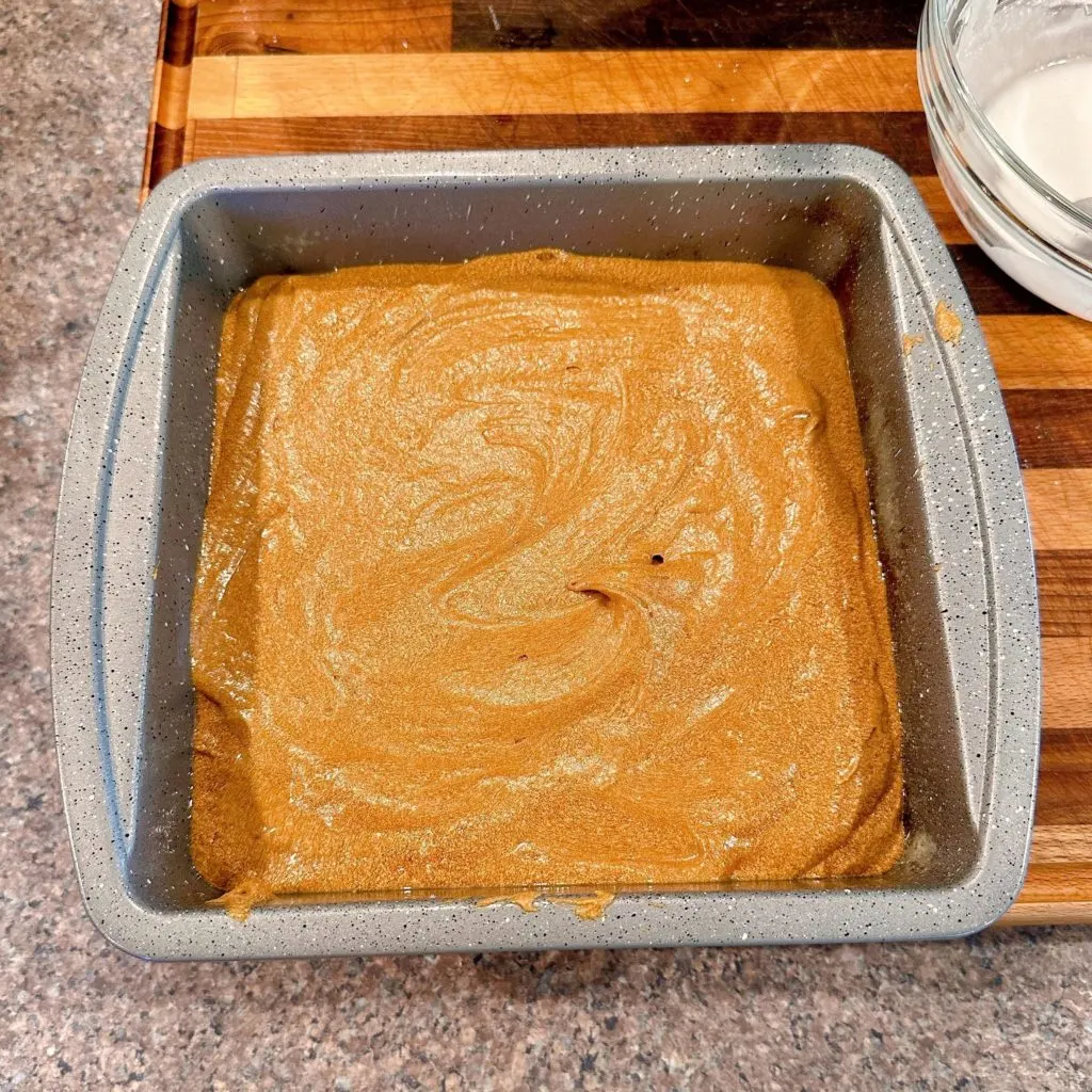 Pouring cake batter into a prepared baking dish.