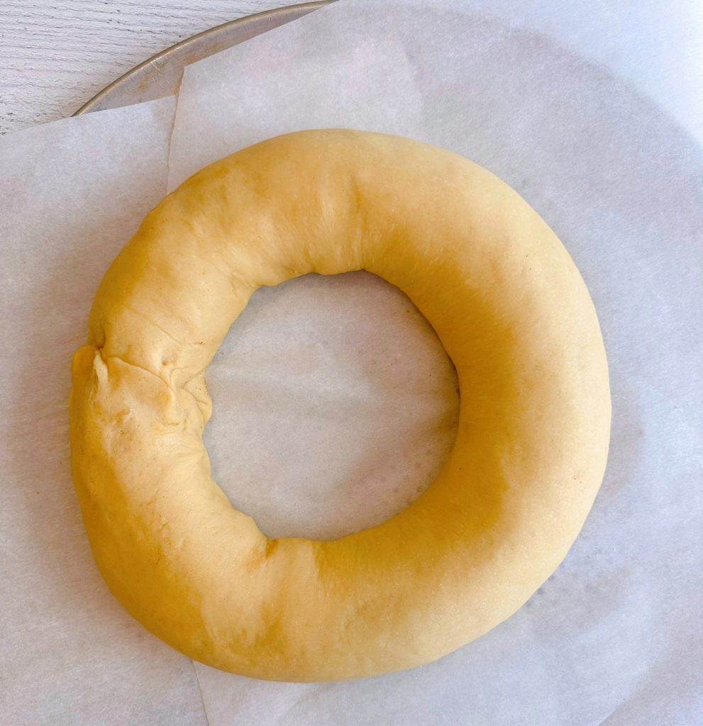 Sweet dough in the shape of a ring on a parchment lined baking sheet.