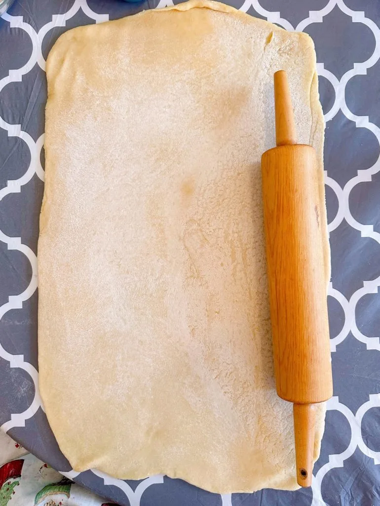 Rolled dough on floured surface with a rolling pin.