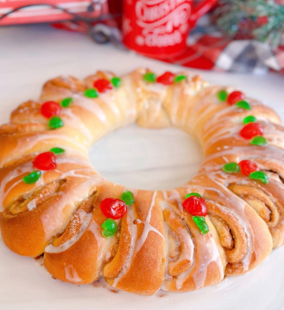 Swedish Tea Ring on a white board, with a beautiful white glaze and cherry holly.