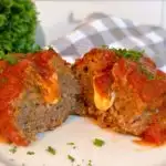 Individual Italian Meatloaf cut in half revealing melted cheese stuffed in the center.
