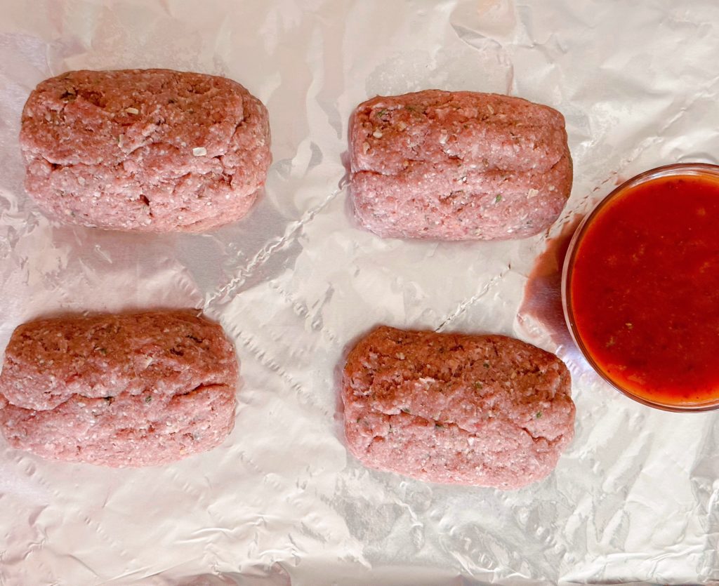 Mini-Italian meatloaves on a prepared baking sheet.