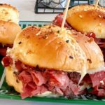 Close-up of a pastrami and swiss cheese slider on a decorative football plate.