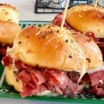 Close-up of a pastrami and swiss cheese slider on a decorative football plate.