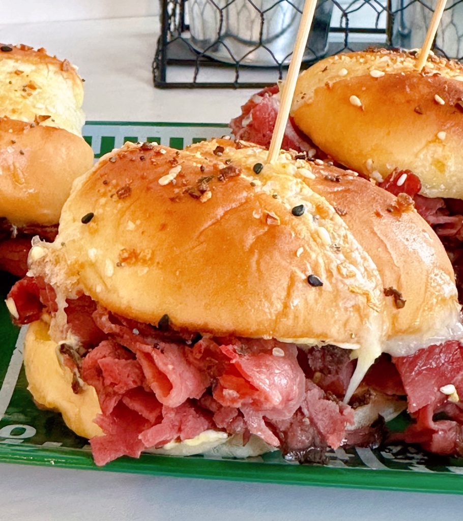 Close-up of a pastrami and swiss cheese slider on a decorative football plate.