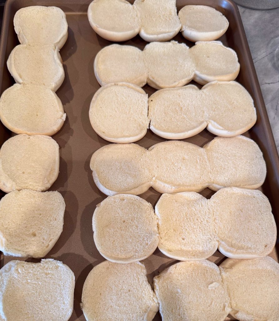 Buns sliced in half and placed on a baking sheet to toast in broiler.