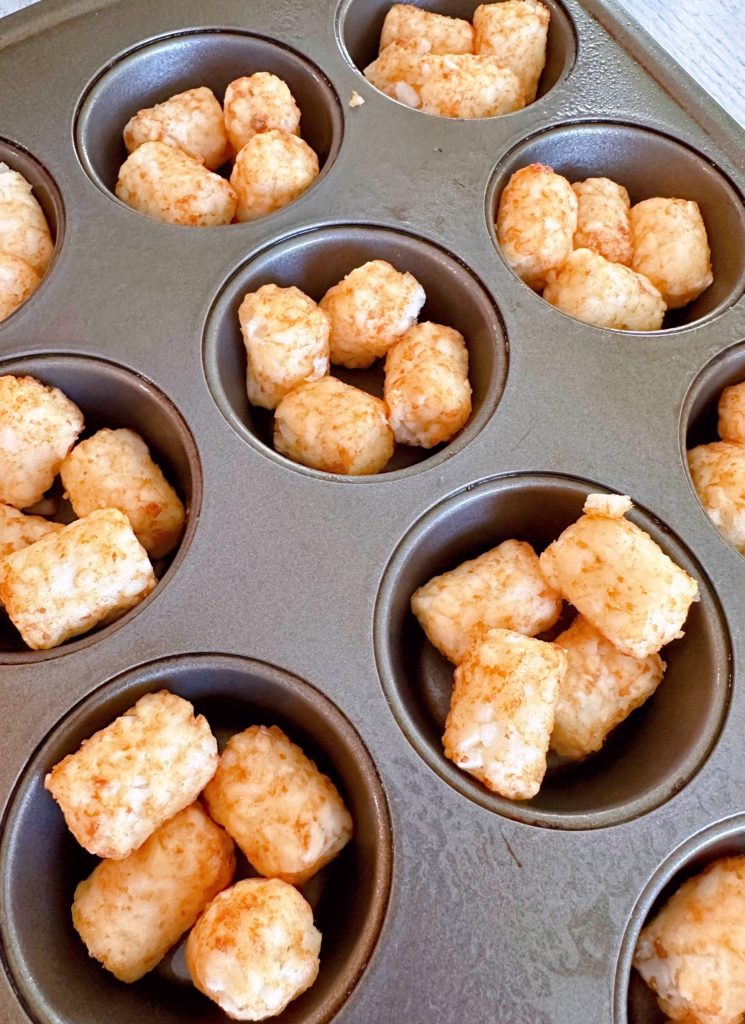 Tater tots in a prepared muffin tin. 