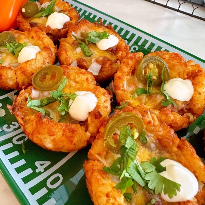 Chili Tater Tot cups with garnishes on football platter for game day snacks.