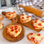 Mini pepperoni Pizzas on little wooden cutting boards.