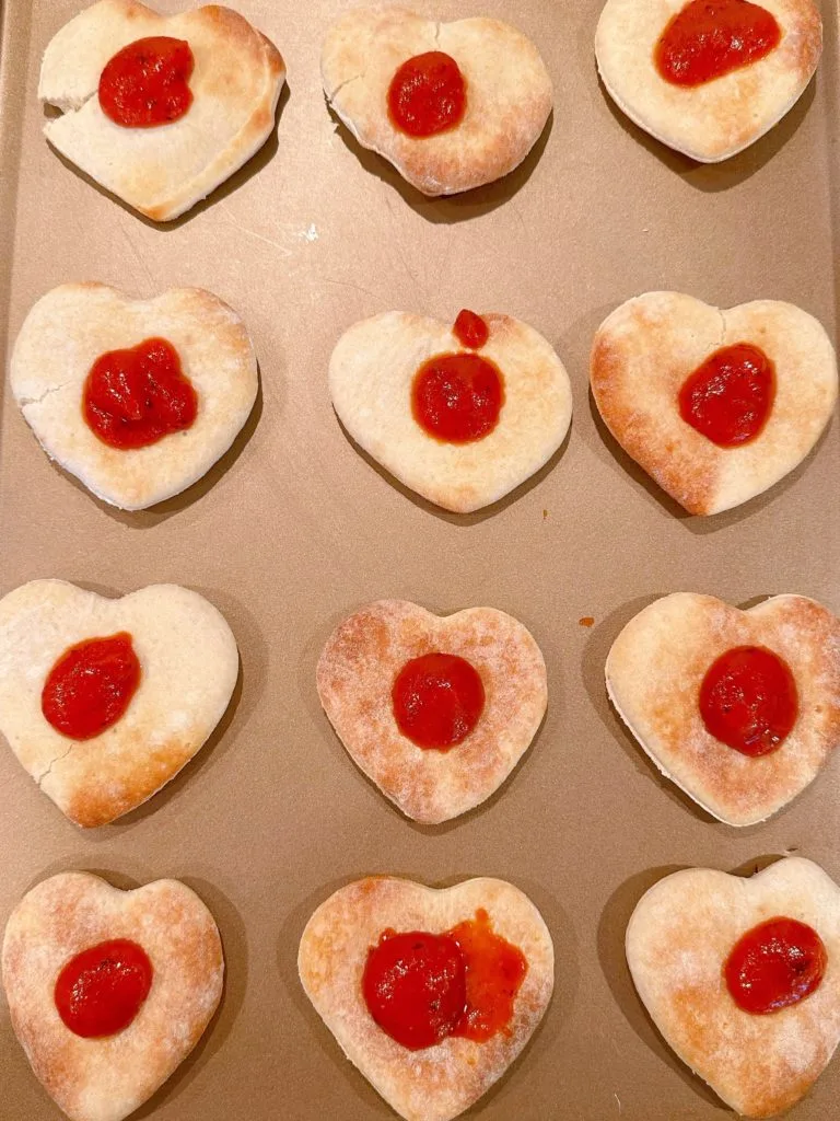 Pizza sauce in the center of each pre-baked heart pizza crust.