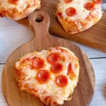 Mini pepperoni pizzas on cutting boards.