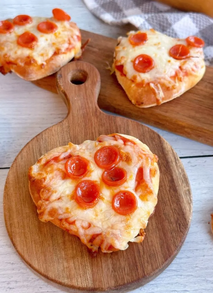 Mini pepperoni pizzas on cutting boards.