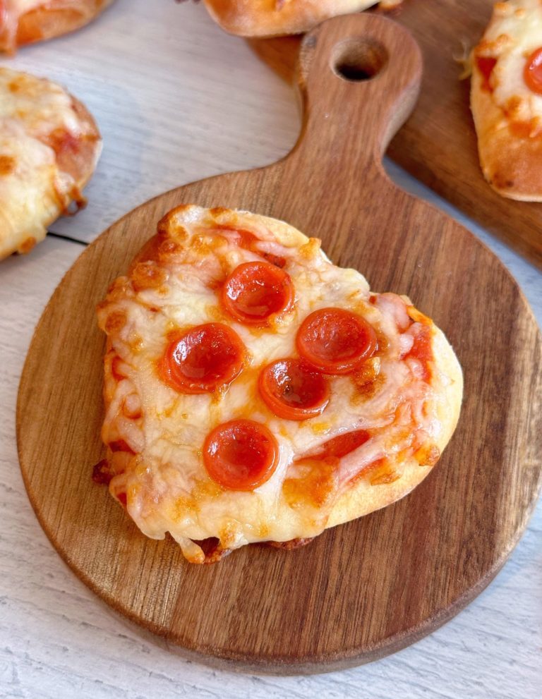 Close-up photo of a mini air fryer pepperoni pizza on a small cutting board.