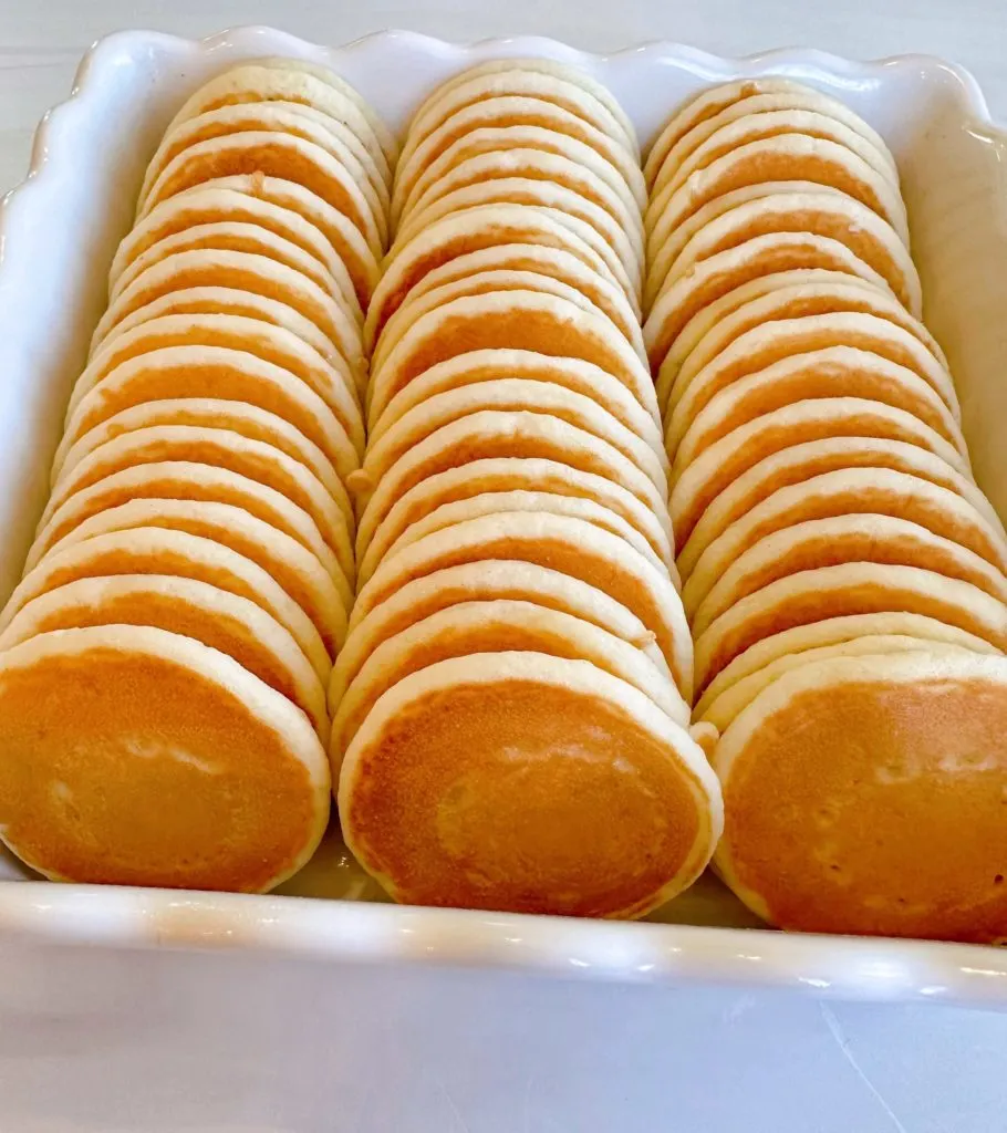 Mini-pancakes lined up in an 8x8 baking dish in three rows.