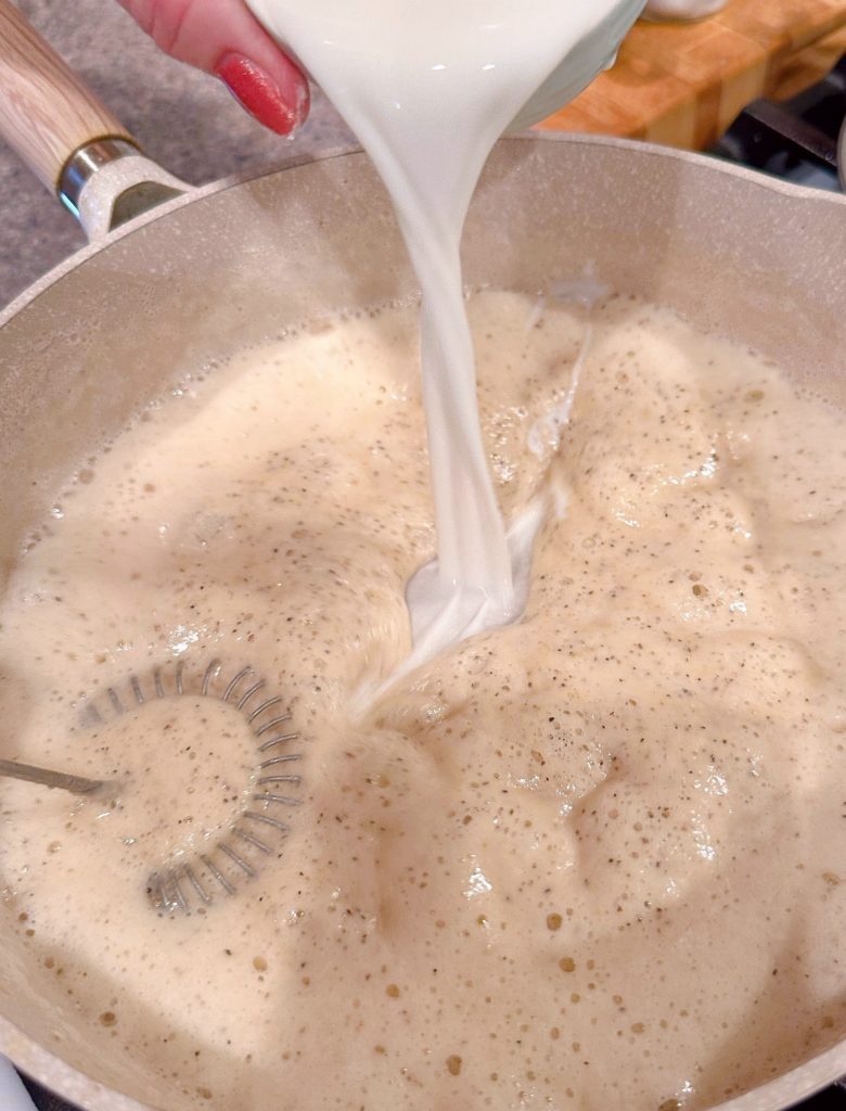 Slowly add cream to roux to create cream sauce.