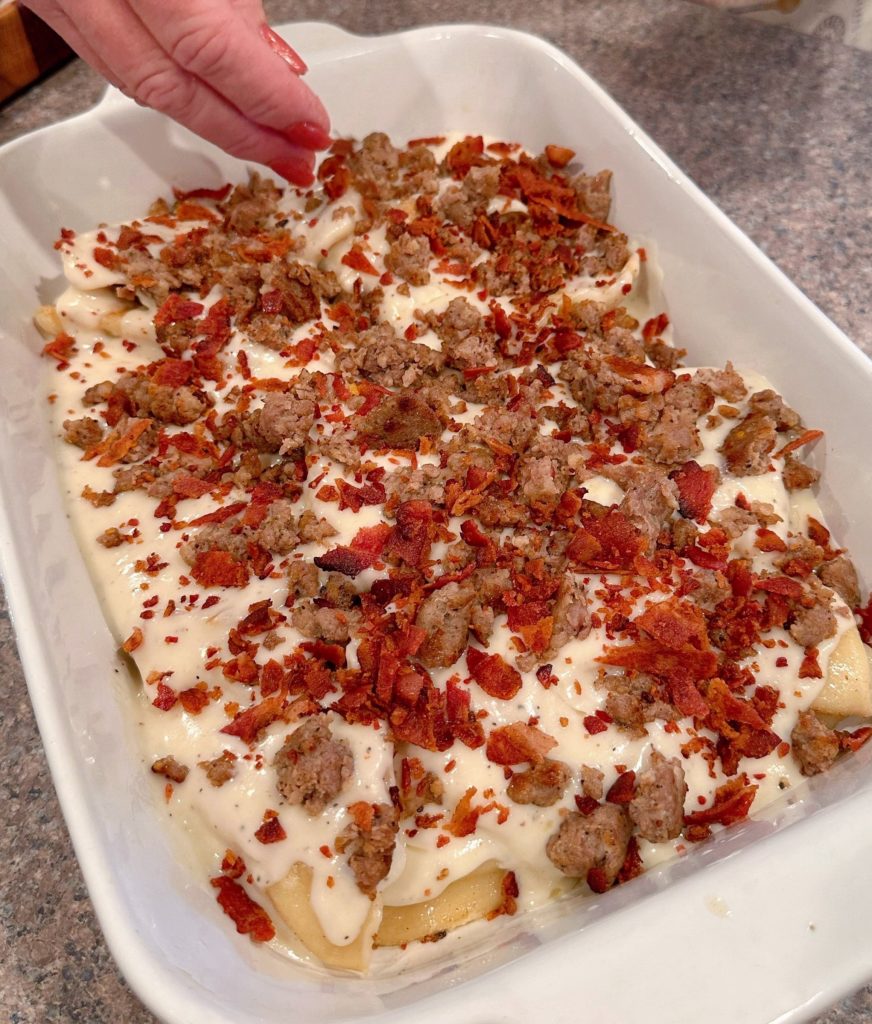 Sprinkling bacon and sausage over the top of the Pierogies casserole.