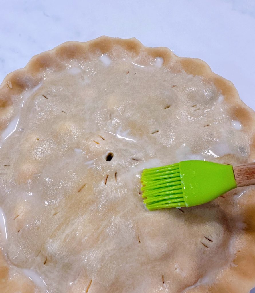 Brushing the top of pie crust with milk.