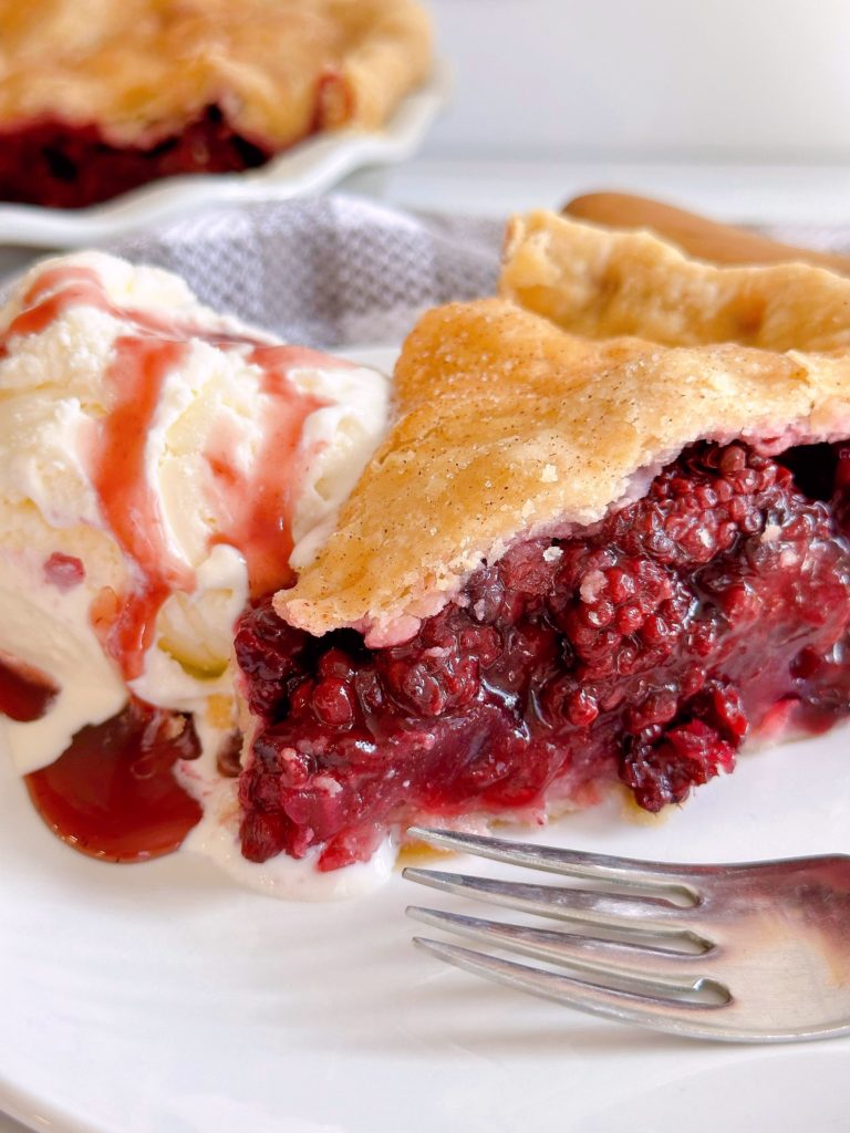 Close-up photo of slice of Blackberry pie with ice cream.