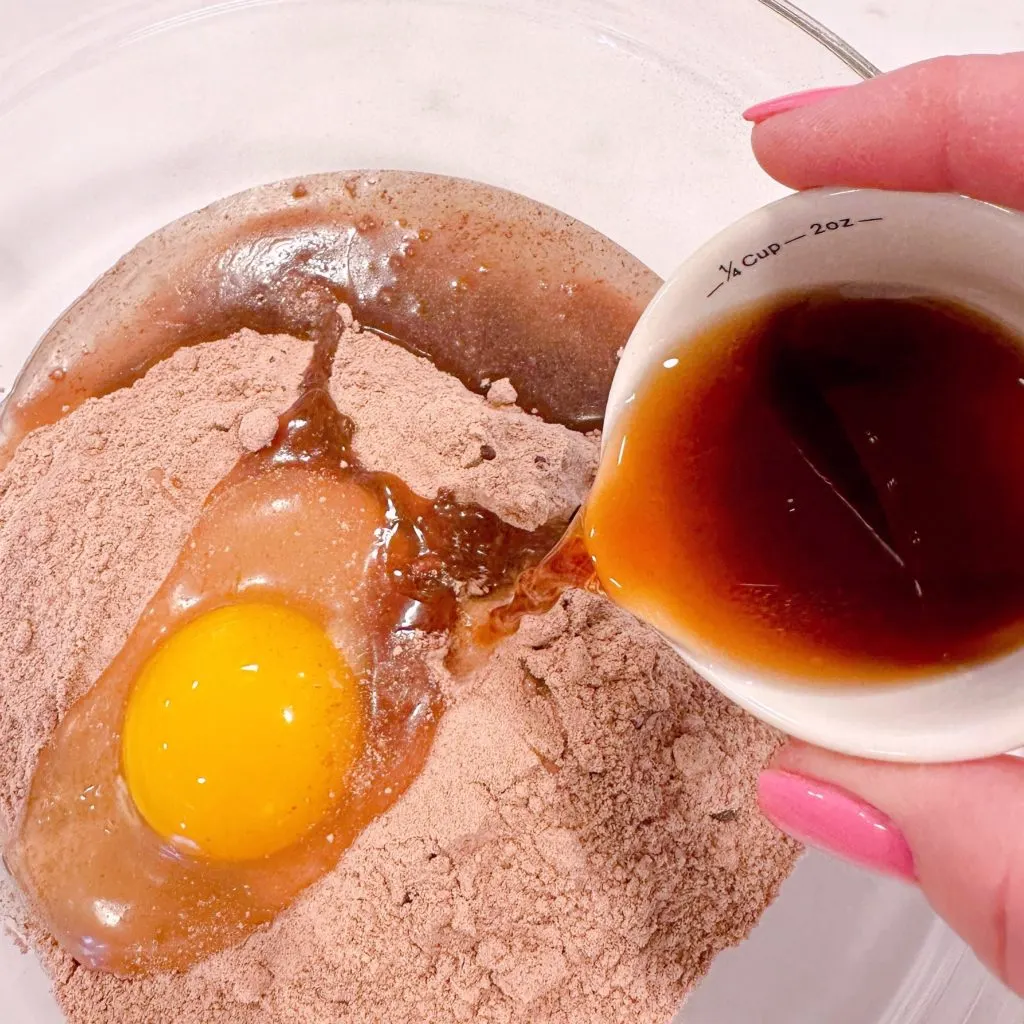 Adding choffy to brownie mix with egg and vegetable oil.