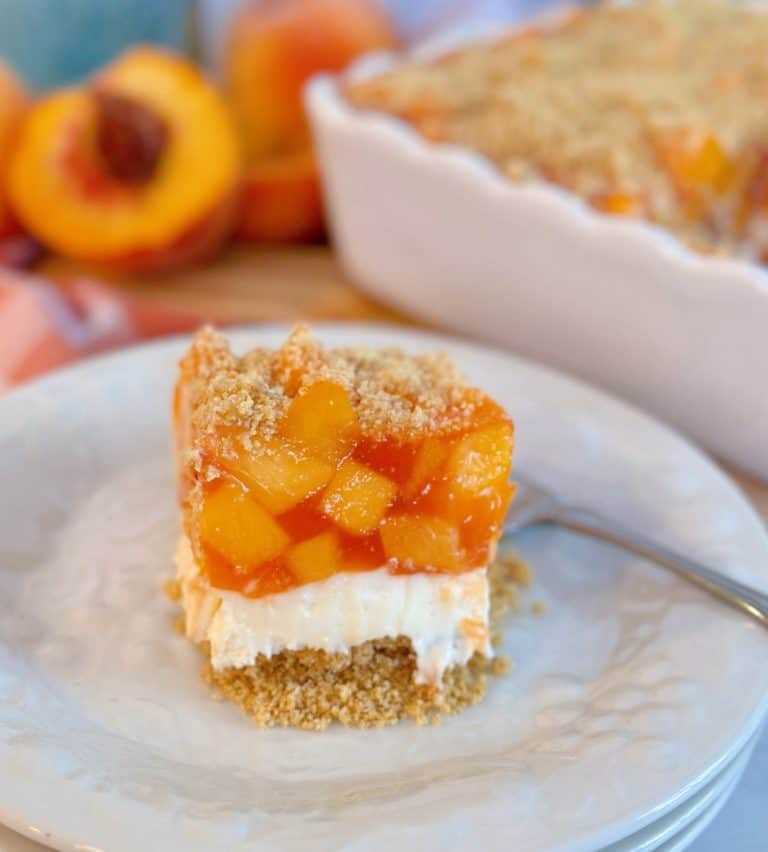 Layered Peach Delight Dessert sliced and on a plate with a fork.