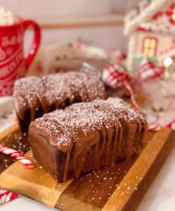Two mini Chocolate Peppermint Loaf cakes on a mini cutting board with Christmas stuff in the background.