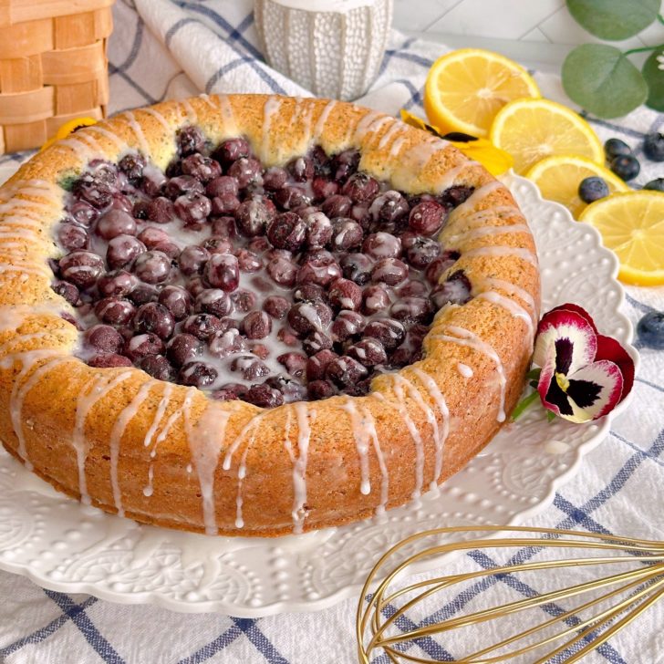 Blueberry-Lemon Poppy Seed Cake on a cake plate with citrus glaze.