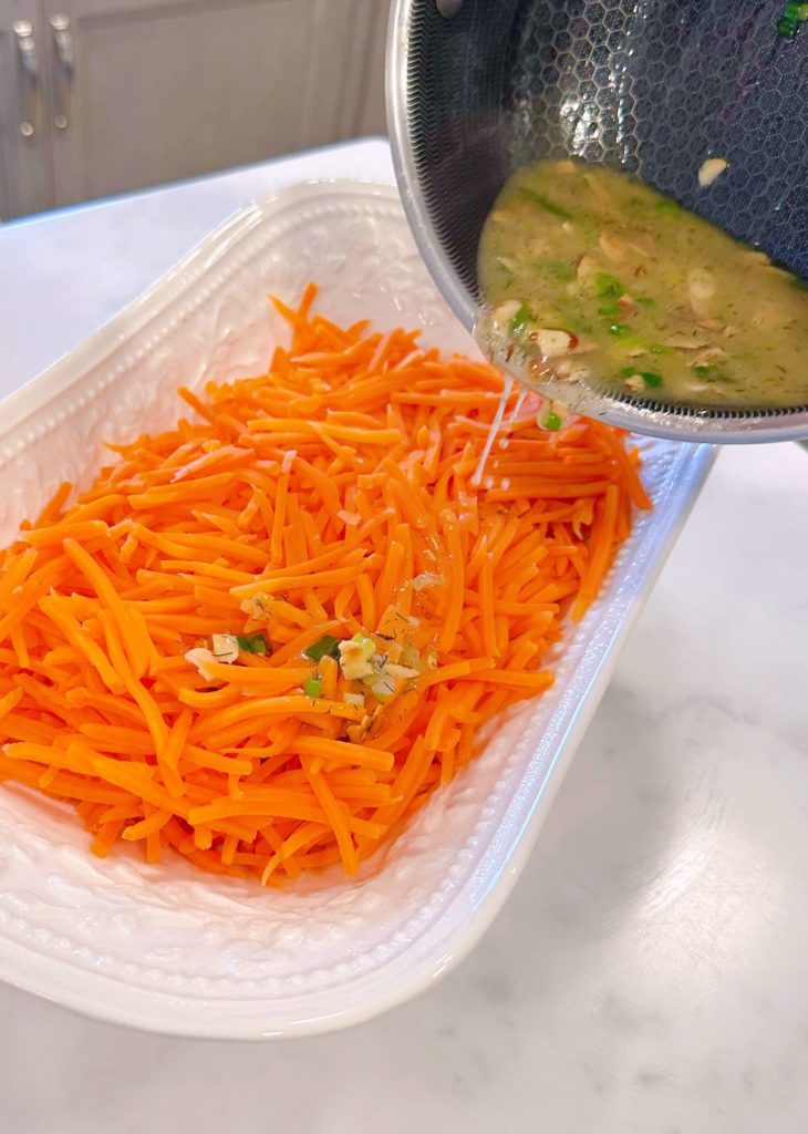 Pouring almond butter sauce over carrots.