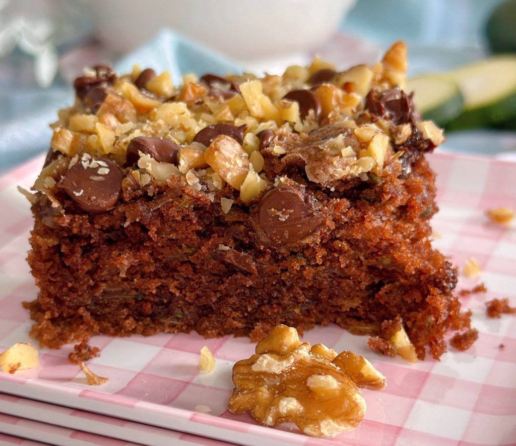 Chocolate Zucchini Walnut Cake cut into squares and served on pink plates.