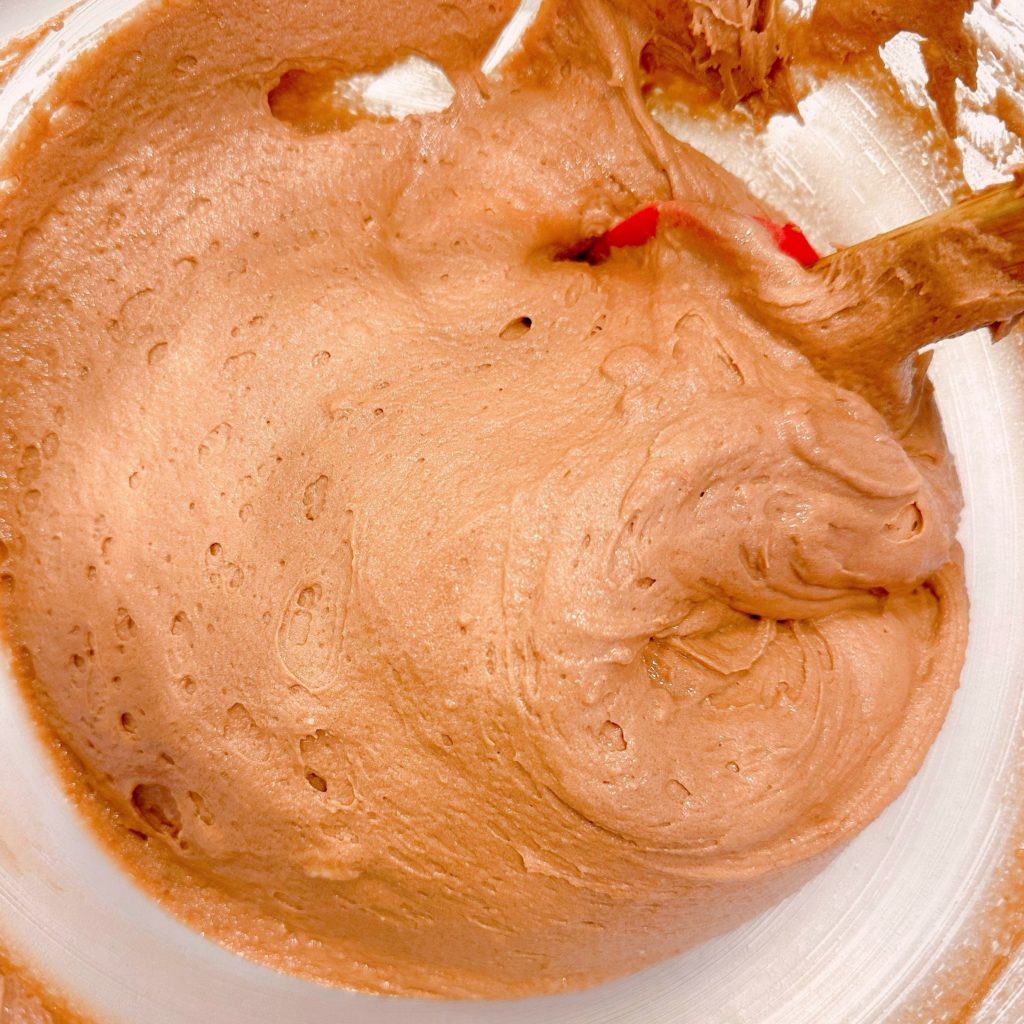 Cake batter is mixed in a mixing bowl.