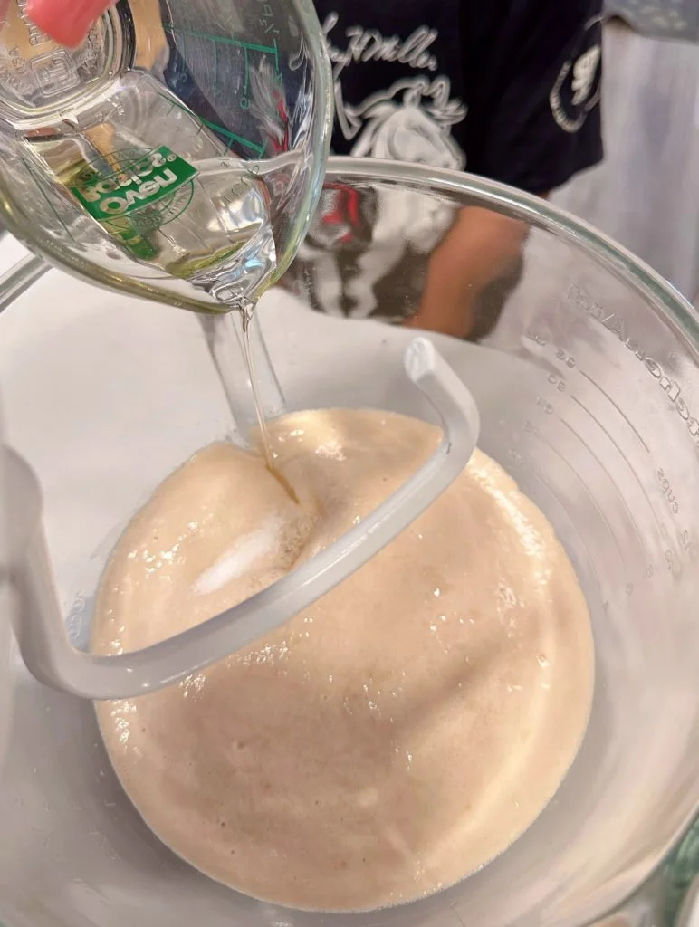 Adding salt and oil to yeast mixture.