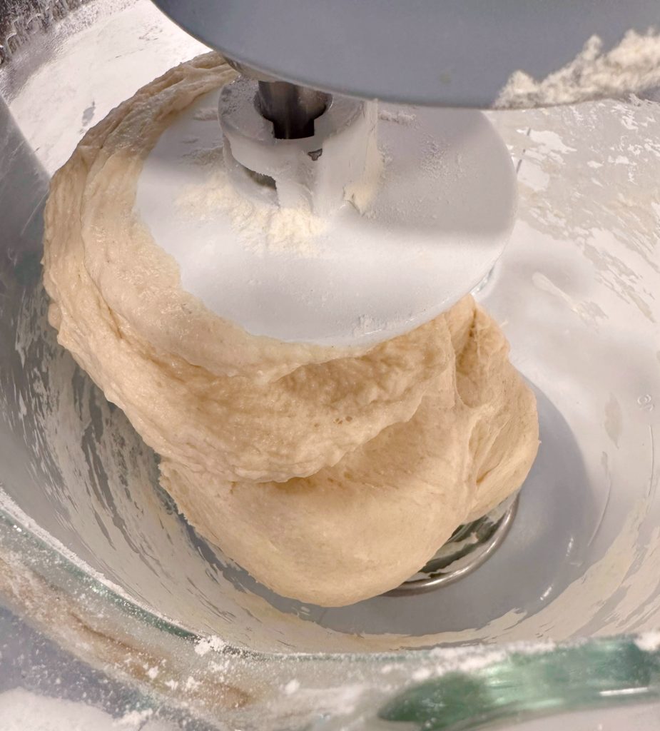 Dough clinging to the dough hook and cleaned away from the sides of the bowl.